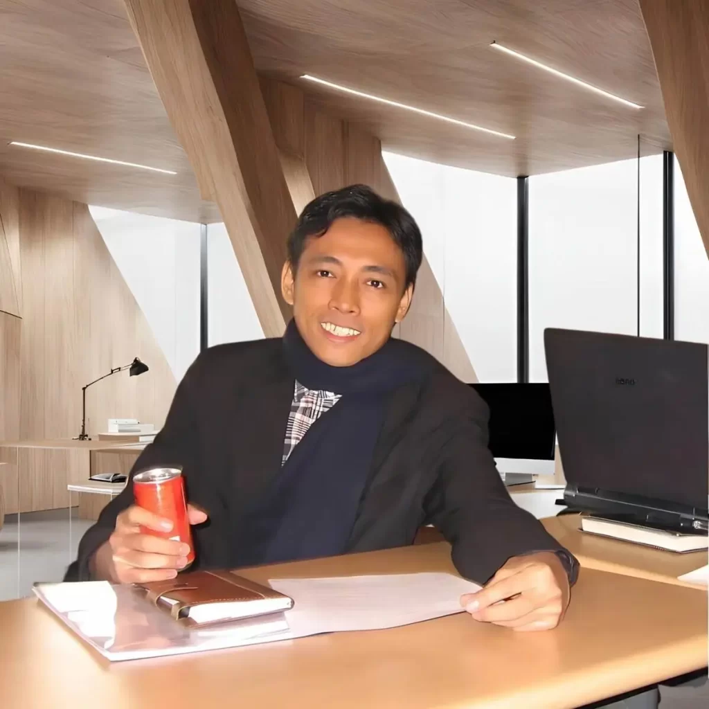 A man sitting at a desk beside a laptop computer